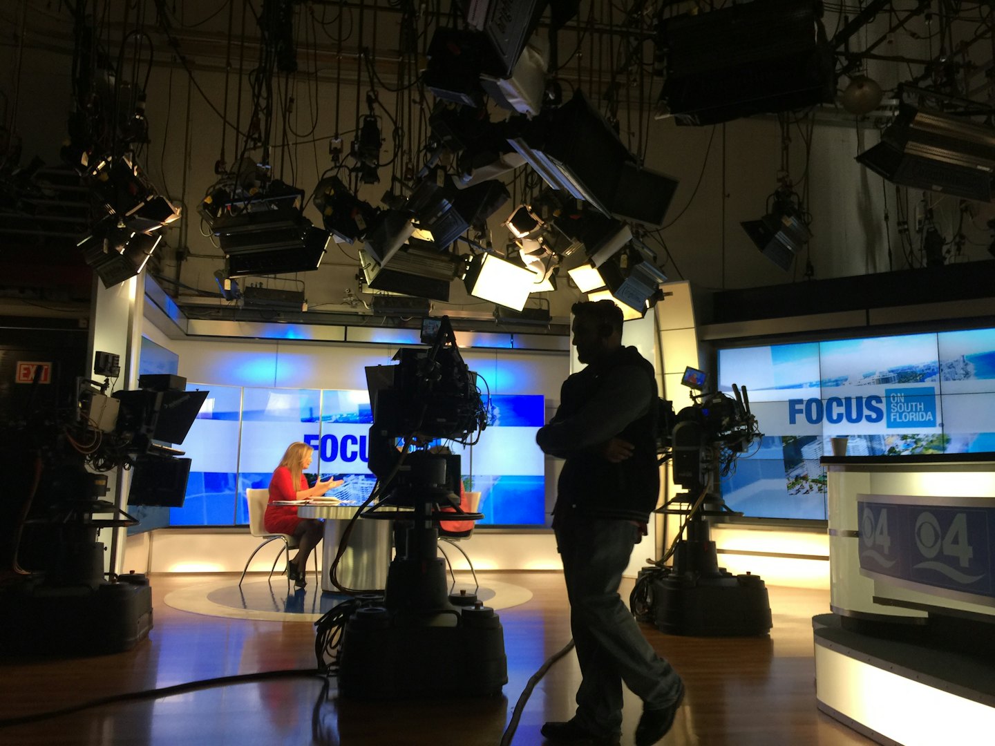News anchor at desk preparing for broadcast in studio.