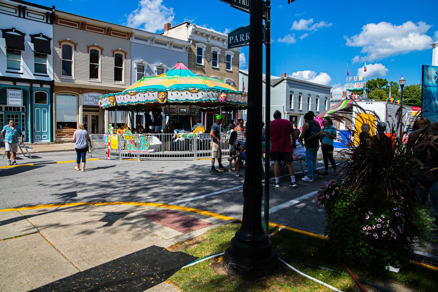 Colorful carousel at a sunny street fair with people.