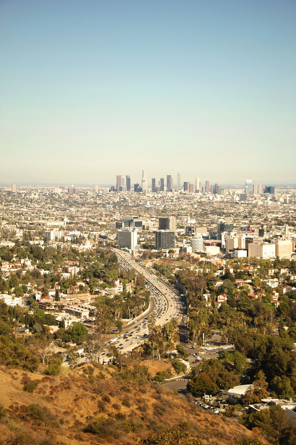 Multi-lane freeway winding through a sprawling city with skyscrapers.