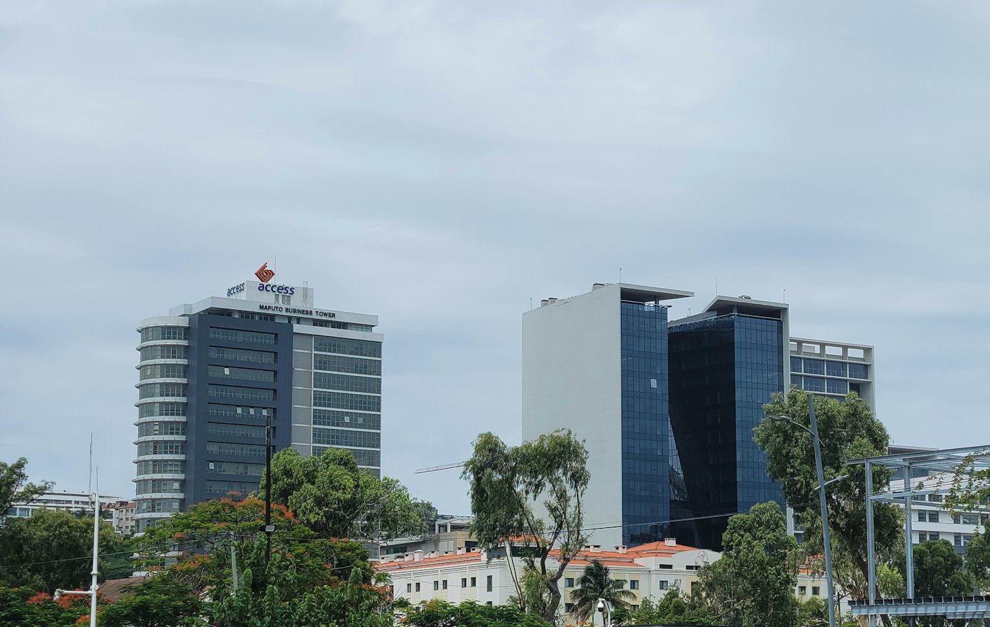 Modern office towers rise above trees in the Maputo skyline.