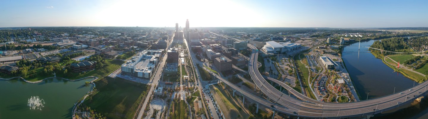 An expansive cityscape features tall buildings, highways, and a winding river.